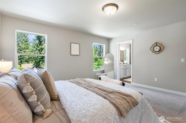 bedroom with connected bathroom, baseboards, and light carpet