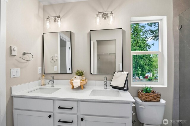 full bath with double vanity, a sink, and toilet