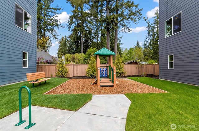 view of play area with a lawn, a patio, and a fenced backyard