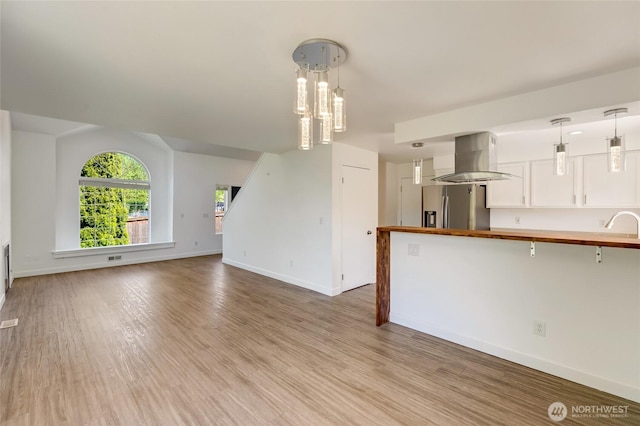 unfurnished living room featuring baseboards, wood finished floors, a chandelier, and a sink
