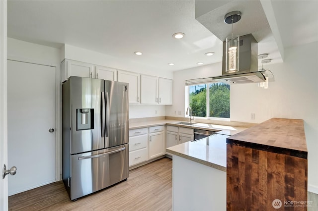 kitchen with stainless steel fridge, island exhaust hood, a sink, light countertops, and light wood-type flooring