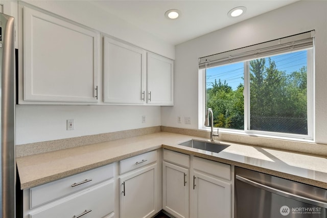 kitchen with appliances with stainless steel finishes, a sink, white cabinets, recessed lighting, and light stone countertops
