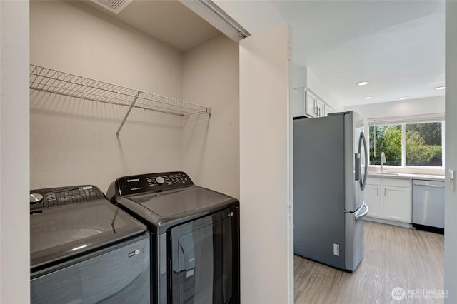 washroom with independent washer and dryer, light wood finished floors, and recessed lighting