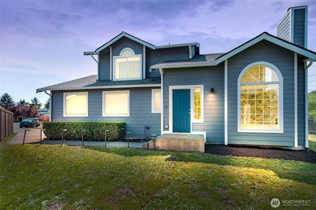 view of front of house featuring a front lawn, a chimney, and a shingled roof