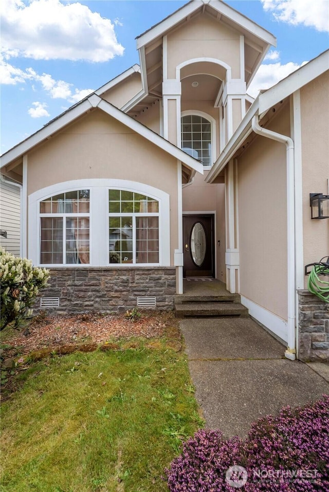 property entrance featuring stone siding and stucco siding