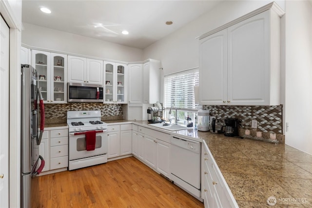 kitchen featuring backsplash, stainless steel appliances, white cabinets, and a sink
