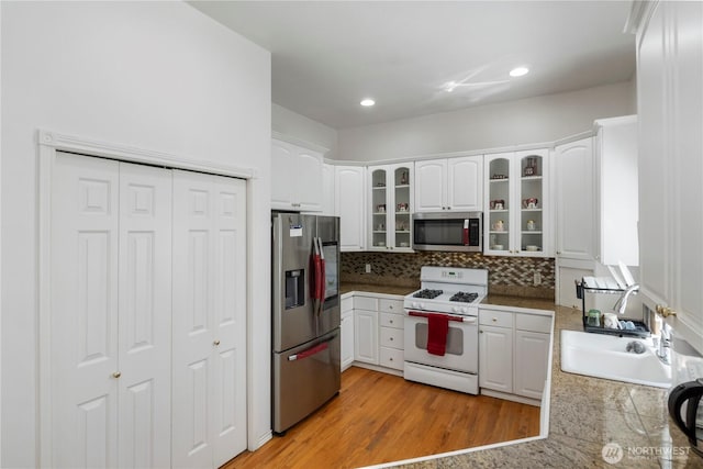 kitchen with white cabinets, appliances with stainless steel finishes, and glass insert cabinets