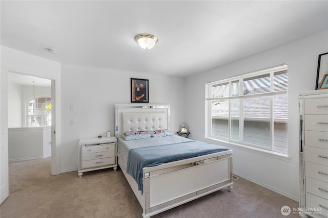 bedroom featuring baseboards, multiple windows, and light colored carpet