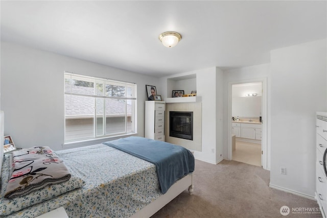 bedroom with baseboards, a fireplace, connected bathroom, and carpet
