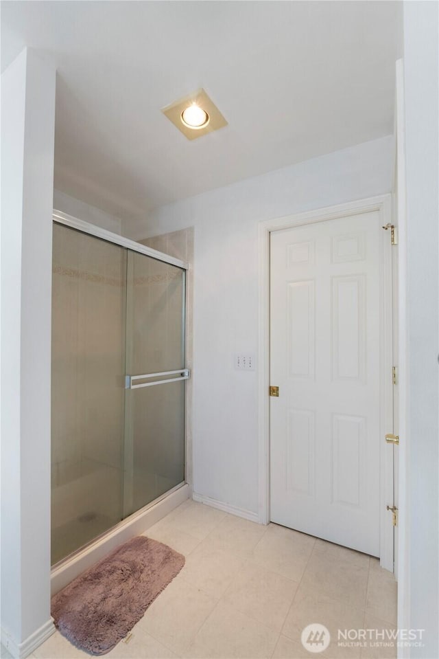 full bathroom with a stall shower, baseboards, and tile patterned floors