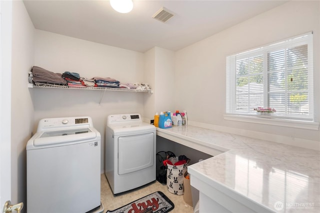 clothes washing area with washing machine and dryer, laundry area, and visible vents
