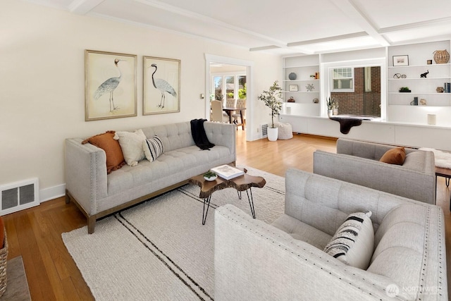 living room with baseboards, beamed ceiling, visible vents, and wood finished floors