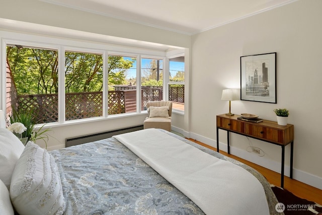 bedroom with baseboards, wood finished floors, baseboard heating, and multiple windows