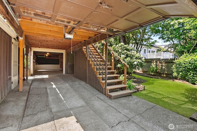 view of patio with fence, stairs, a garage, a carport, and driveway