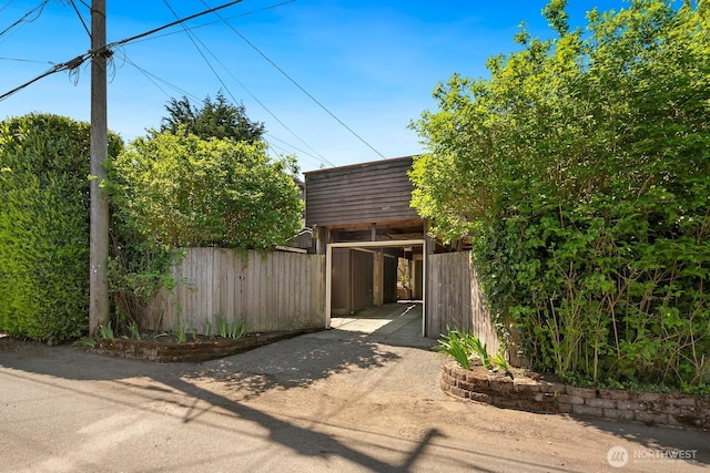 exterior space with fence, a carport, and dirt driveway