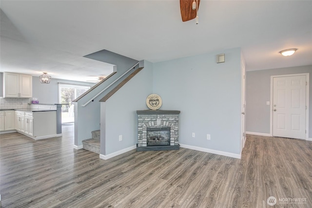 293 Glacier Ct SE, Ocean Shores, WA 98569 - unfurnished living room featuring stairway, baseboards, a stone fireplace, and wood finished floors