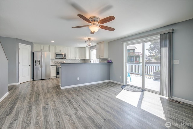 293 Glacier Ct SE, Ocean Shores, WA 98569 - kitchen with wood finished floors, a ceiling fan, backsplash, and stainless steel appliances