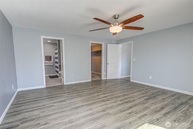 293 Glacier Ct SE, Ocean Shores, WA 98569 - unfurnished bedroom with baseboards, a closet, wood finished floors, and a walk in closet