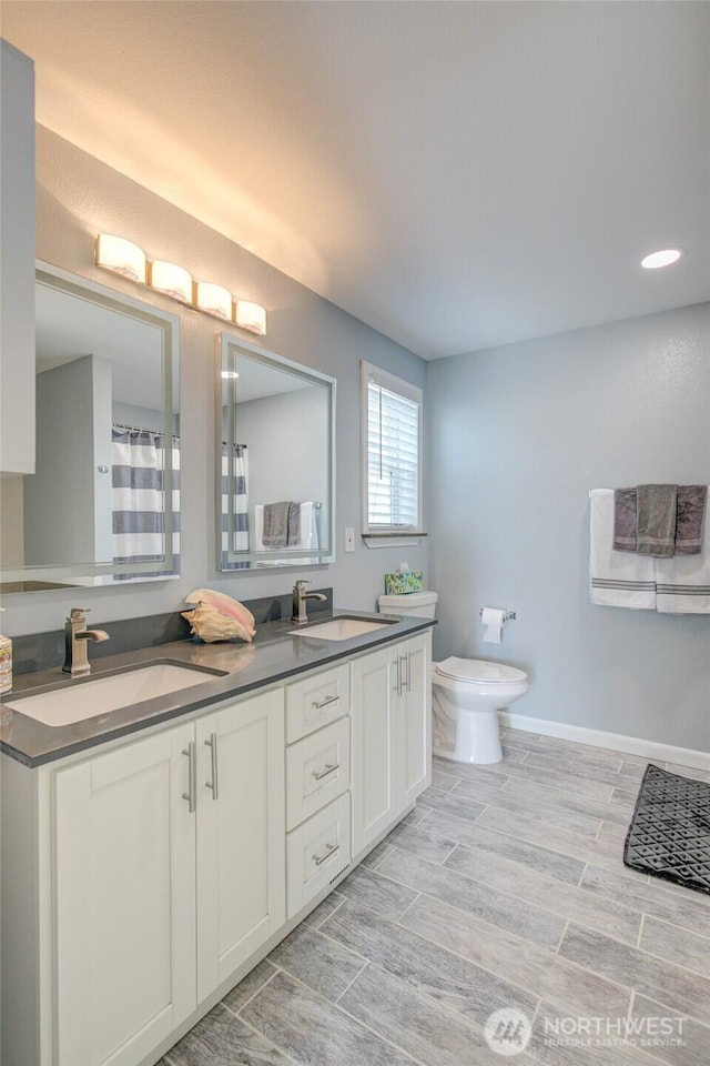 293 Glacier Ct SE, Ocean Shores, WA 98569 - bathroom with a sink, wood finish floors, toilet, and double vanity