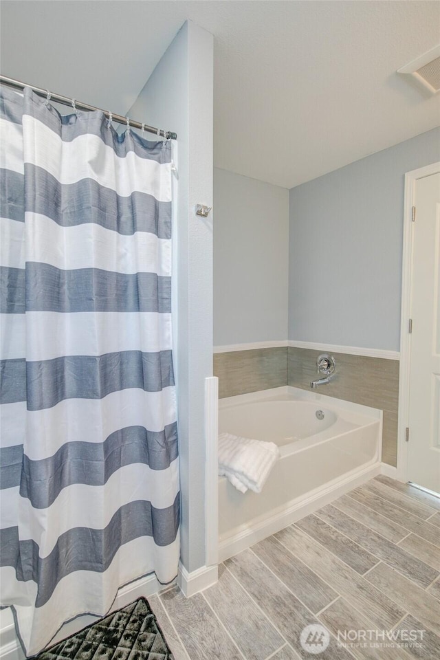 293 Glacier Ct SE, Ocean Shores, WA 98569 - full bathroom featuring wood tiled floor, a garden tub, and a shower with shower curtain