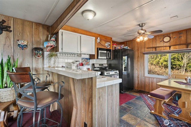 51 N Old Mill Hill Rd, Hoodsport, WA 98548 - kitchen featuring stainless steel appliances, tile countertops, wooden walls, stone finish flooring, and a peninsula