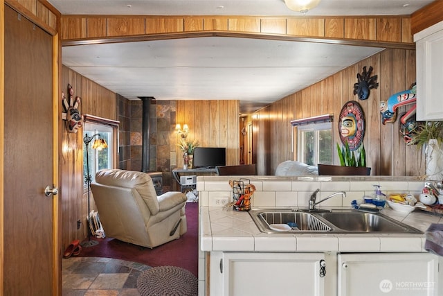 51 N Old Mill Hill Rd, Hoodsport, WA 98548 - kitchen featuring tile counters, wood walls, stone finish floors, white cabinets, and open floor plan