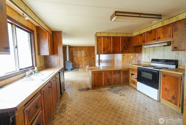 kitchen featuring electric range, a sink, a wood stove, light countertops, and under cabinet range hood