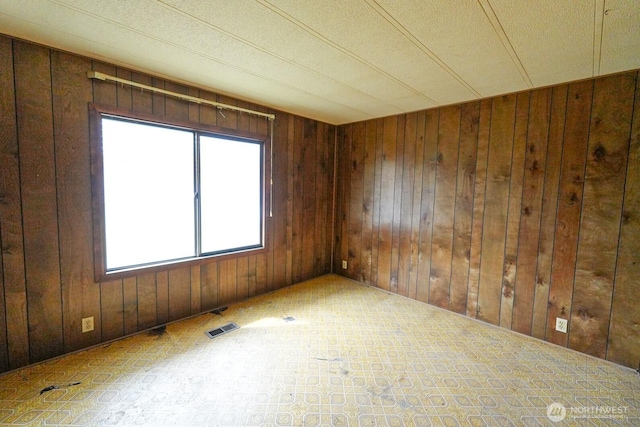 spare room with wooden walls and visible vents