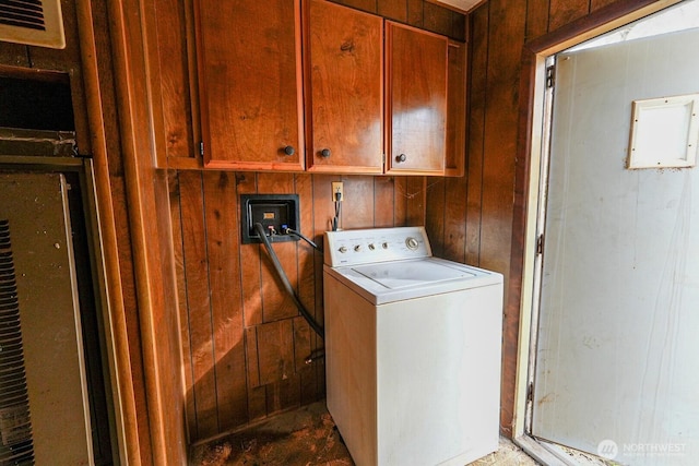 laundry room featuring cabinet space, wood walls, and washer / dryer
