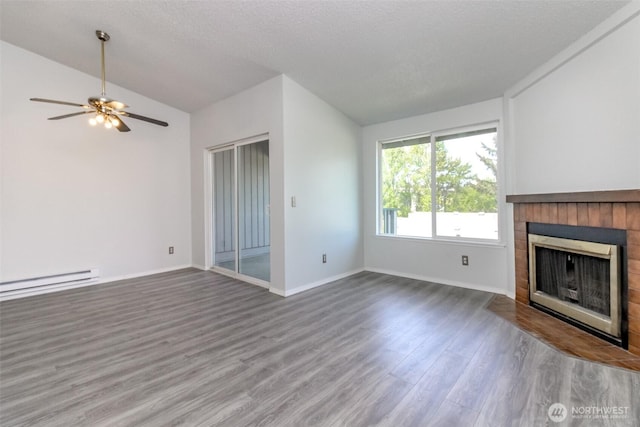 unfurnished living room featuring baseboards, a fireplace with flush hearth, wood finished floors, a baseboard radiator, and vaulted ceiling