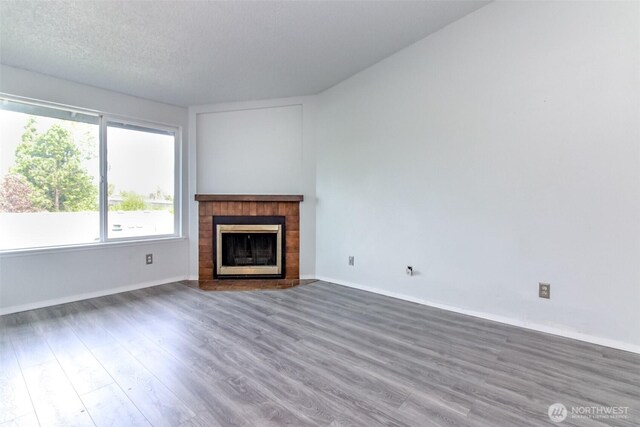 unfurnished living room with baseboards, a fireplace with flush hearth, and wood finished floors