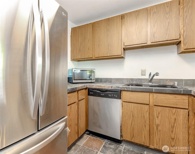 kitchen featuring a sink, stone finish flooring, dark countertops, and stainless steel appliances