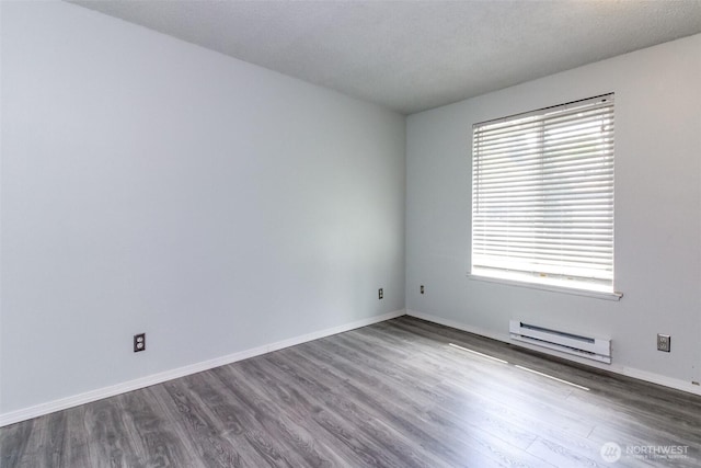 unfurnished room featuring dark wood-style flooring, baseboards, and a baseboard radiator