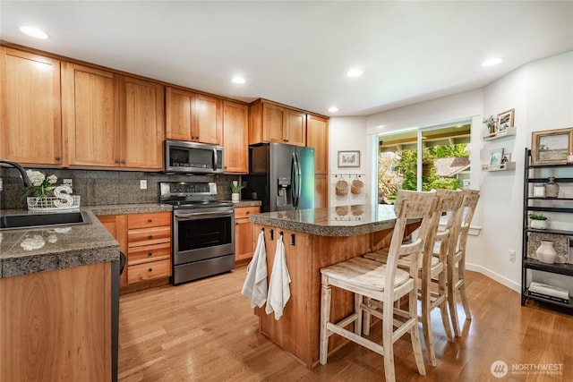 kitchen with tile counters, a sink, light wood-style floors, and appliances with stainless steel finishes