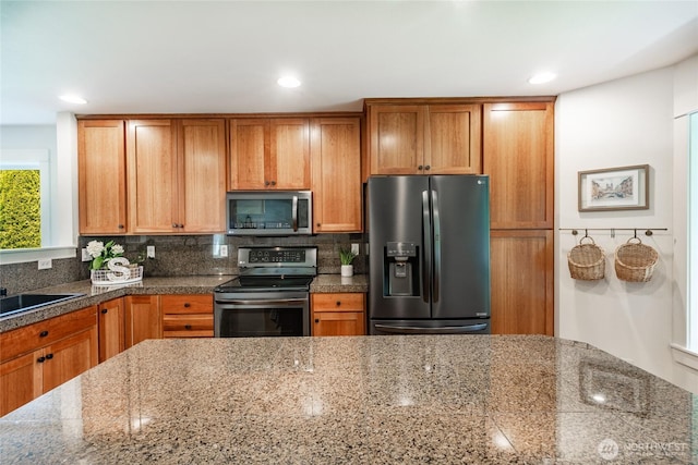 kitchen with recessed lighting, tile countertops, brown cabinets, tasteful backsplash, and appliances with stainless steel finishes