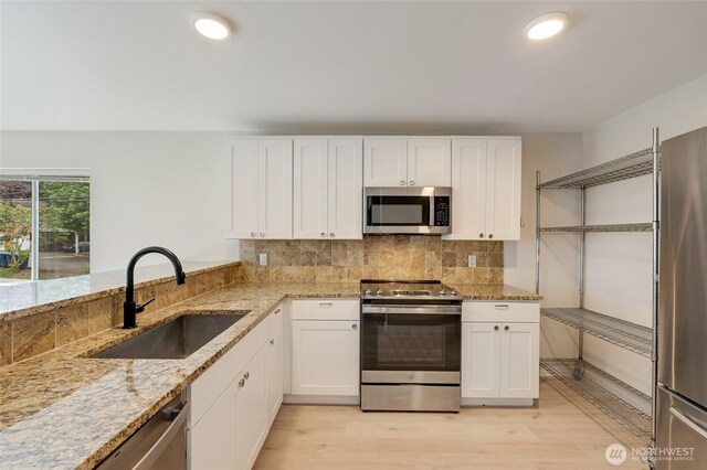16820 6th Ave W Unit A4, Lynnwood, WA 98037 - kitchen with appliances with stainless steel finishes, a sink, light stone counters, white cabinetry, and light wood-style floors