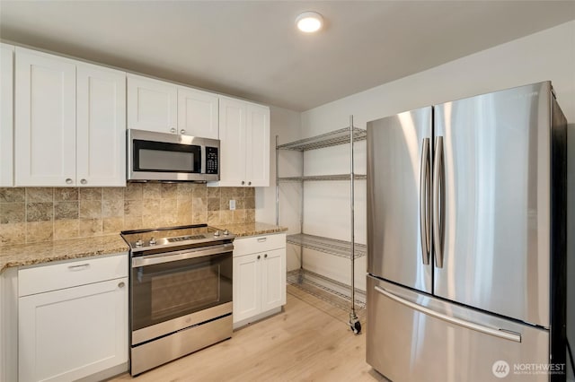 16820 6th Ave W Unit A4, Lynnwood, WA 98037 - kitchen with appliances with stainless steel finishes, white cabinets, light wood finished floors, tasteful backsplash, and light stone counters