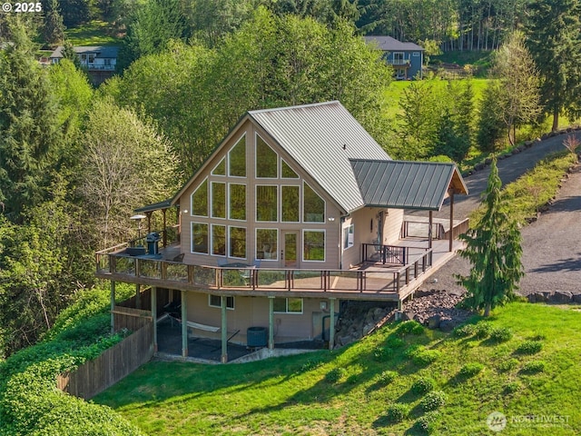 back of property featuring central AC unit, a wooden deck, metal roof, and a lawn
