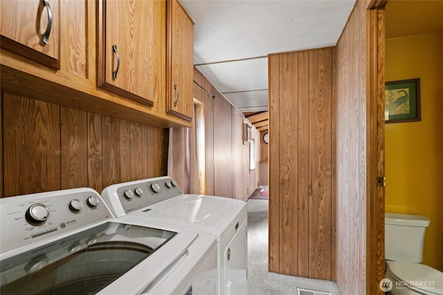 washroom with cabinet space, separate washer and dryer, and light colored carpet