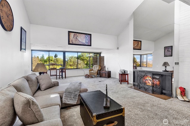 carpeted living area featuring high vaulted ceiling, a fireplace with flush hearth, and a healthy amount of sunlight