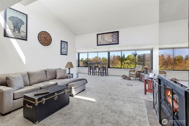 carpeted living room with high vaulted ceiling