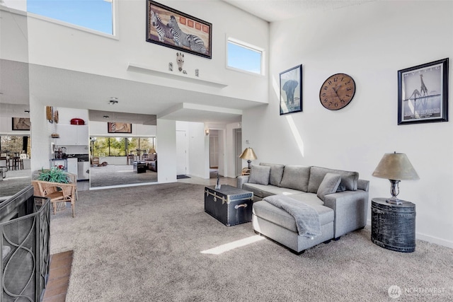 carpeted living area featuring baseboards and a high ceiling
