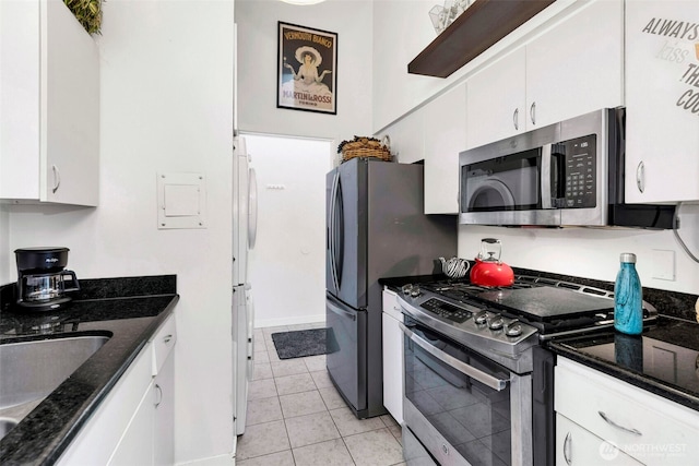 kitchen featuring dark stone counters, white cabinets, and stainless steel appliances