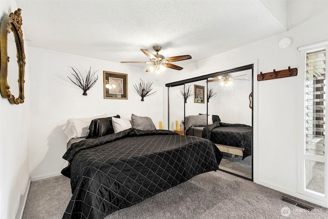 bedroom with ceiling fan, a textured ceiling, visible vents, baseboards, and carpet