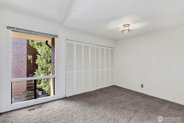 unfurnished bedroom featuring carpet floors, a closet, a textured ceiling, and visible vents