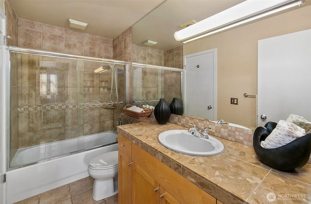full bath featuring vanity, bath / shower combo with glass door, tile patterned flooring, and toilet