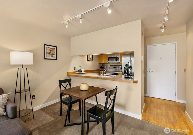 dining space featuring baseboards, track lighting, and wood finished floors