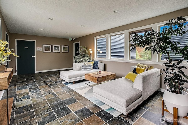 living room with stone tile floors, recessed lighting, baseboards, and a textured ceiling
