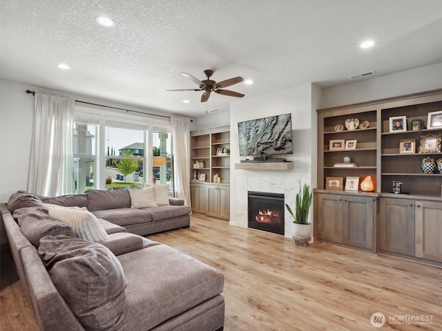 904 E Tanoak Ave, La Center, WA 98629 - living area with a tiled fireplace, recessed lighting, light wood-style floors, ceiling fan, and a textured ceiling