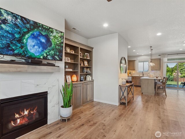 904 E Tanoak Ave, La Center, WA 98629 - living area featuring light wood finished floors, a textured ceiling, recessed lighting, a fireplace, and baseboards